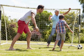 Grandfather, Grandson And Father Playing Football In Garden