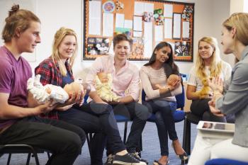 Teacher Helping Students Taking Childcare Course