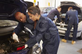 Teacher Helping Student Training To Be Car Mechanics
