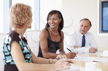 Three Businesspeople Having Meeting In Boardroom