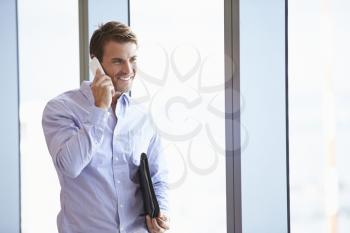 Casually Dressed Businessman Using Mobile Phone In Office