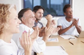 Businesspeople Applauding Colleague In Boardroom
