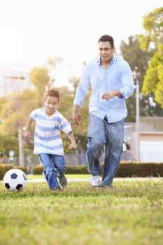 Father With Son Playing Soccer In Park Together