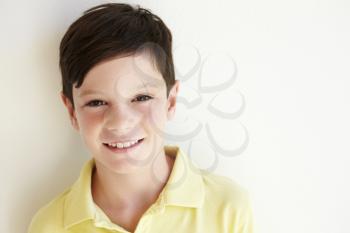 Smiling Young Boy Standing Outdoors Against White Wall