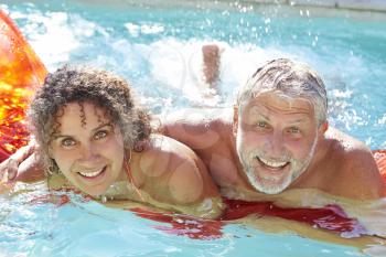 Mature Couple Relaxing On Airbed In Swimming Pool