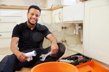 Mixed race plumber sitting in a kitchen, portrait