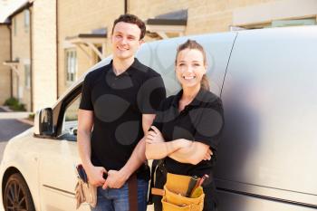 Portrait of male and female trade workers by a van