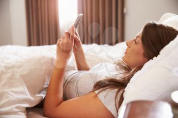 Woman Lying In Bed Whilst Mobile Phone