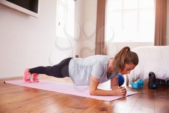 Woman Doing Fitness Exercises On Mat In Bedroom