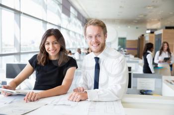 Two young architects working in an office, smiling to camera