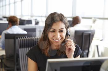 Young woman working in a call centre, holding headset