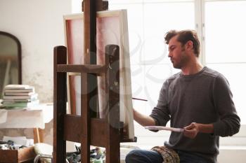 Male Artist Working On Painting In Studio
