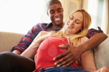 Close Up Of Pregnant Couple At Home Relaxing On Sofa
