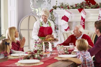 Grandmother Bringing Out Turkey At Family Christmas Meal