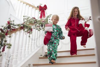 Two Children On Stairs In Pajamas With Christmas Stockings
