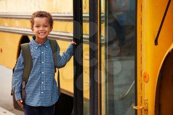 Elementary school boy getting onto a yellow school bus