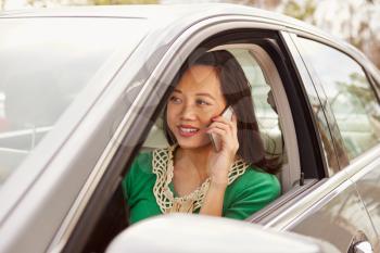 Female Asian driver using phone in a car