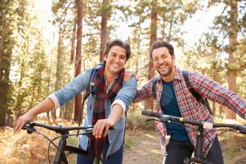 Portrait Of Gay Male Couple Cycling Through Fall Woodland