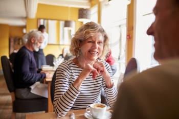 Senior couple have coffee at restaurant, over shoulder view