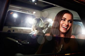 Two women in the back of a limo, photographed by paparazzi