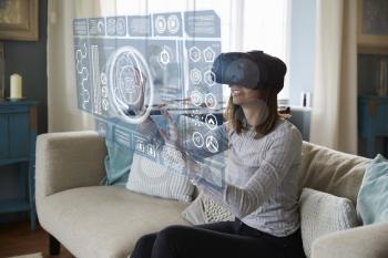 Woman Sits On Sofa At Home Wearing Virtual Reality Headset