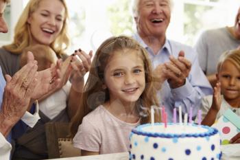 Girl Blows Out Birthday Cake Candles At Family Party