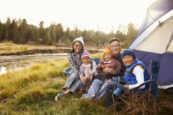 Asian family sitting outside their tent, looking to camera