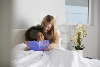 White mum and black daughter looking at card, full length