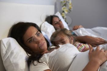 Woman lies awake while her daughter and female partner sleep