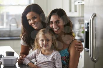 Portrait of female couple in the kitchen with their daughter