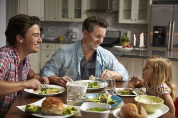 Male gay couple and daughter dining in their kitchen