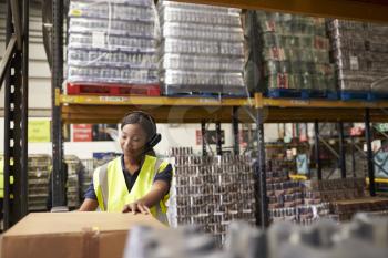 Woman using a barcode reader in a warehouse, wide shot