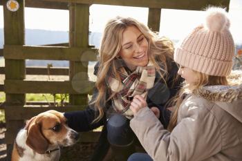 Mother, daughter and dog by a fence in the country, close up