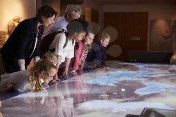 Pupils On School Field Trip To Museum Looking At Map