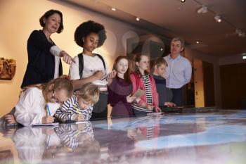 Pupils On Trip To Museum Looking At Map And Making Notes