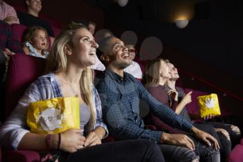 Young Couple In Cinema Watching Film And Eating Popcorn