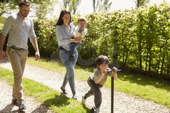 Family Going For Walk In Summer Countryside