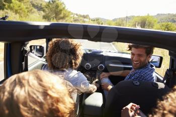 Four friends driving in an open top car, elevated view