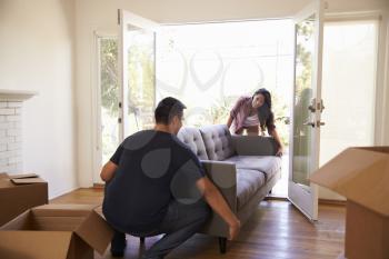 Couple Carrying Sofa Into New Home On Moving Day