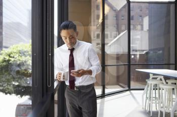 Asian businessman standing in modern office using phone