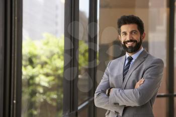 Smiling Hispanic businessman with arms crossed, to camera