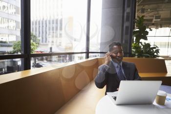 Middle aged black businessman using phone in a modern office