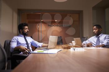 Two middle aged businessman working late in office talking
