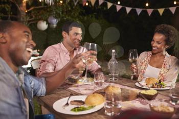 Three young black adults enjoying a garden dinner party