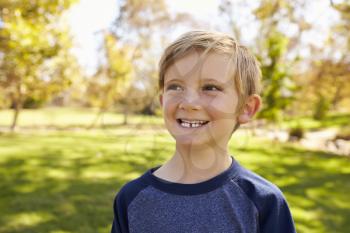 Seven year old Caucasian boy in park looks away from camera