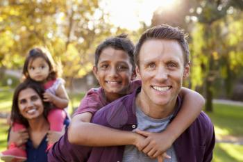 Mixed race parents carry kids piggyback, selective focus
