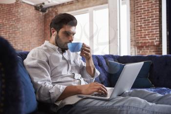 Businessman Working And Drinking Coffee On Sofa In Office