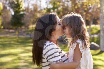 Loving Mother Kissing Daughter In Park