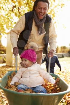 Father In Autumn Garden Gives Daughter Ride In Wheelbarrow
