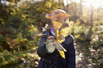 Young Girl Playing With Leaves On Walk In Autumn Countryside